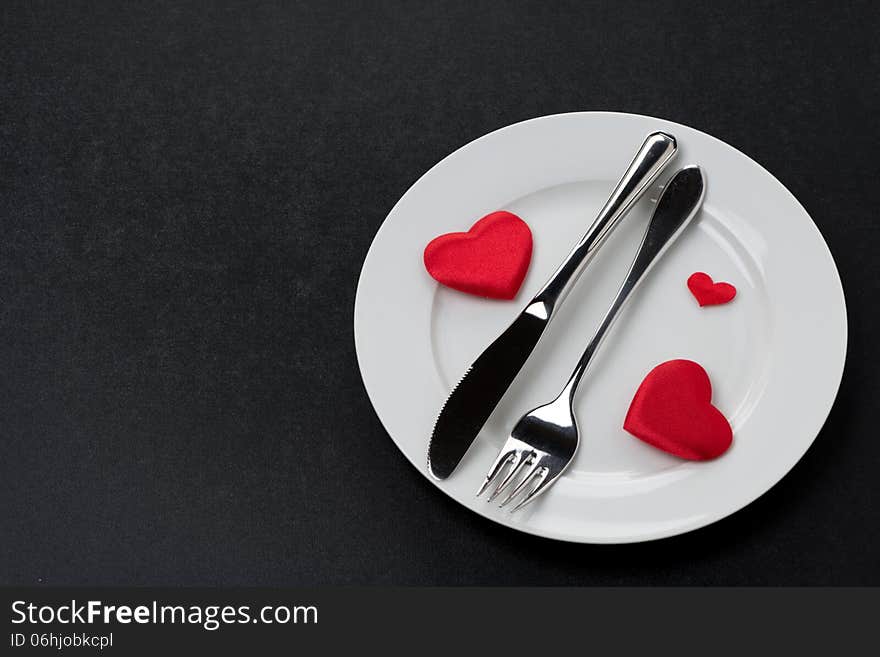 Fork, knife and a red heart on a plate, horizontal