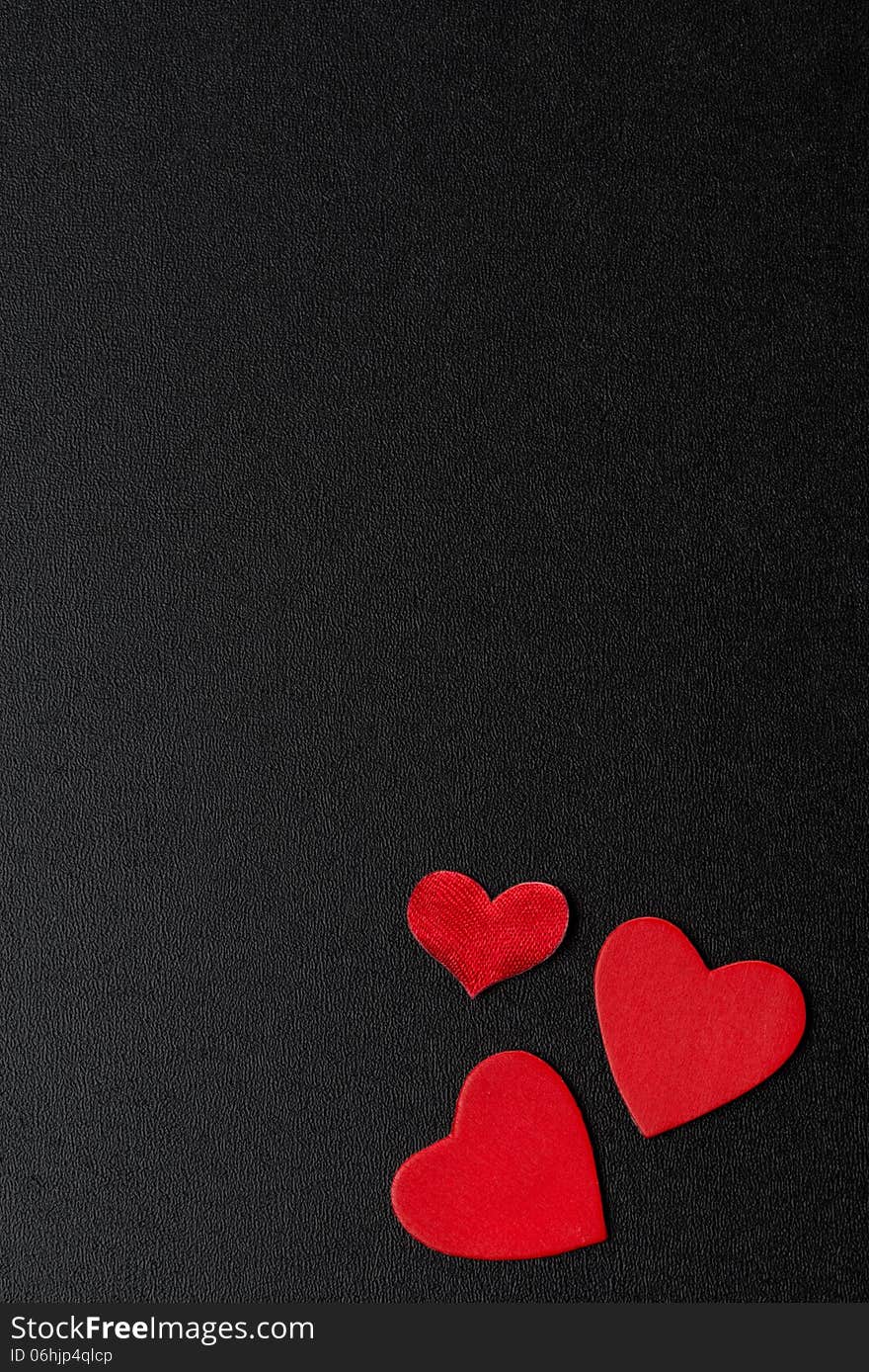 Red hearts on a black background, top view