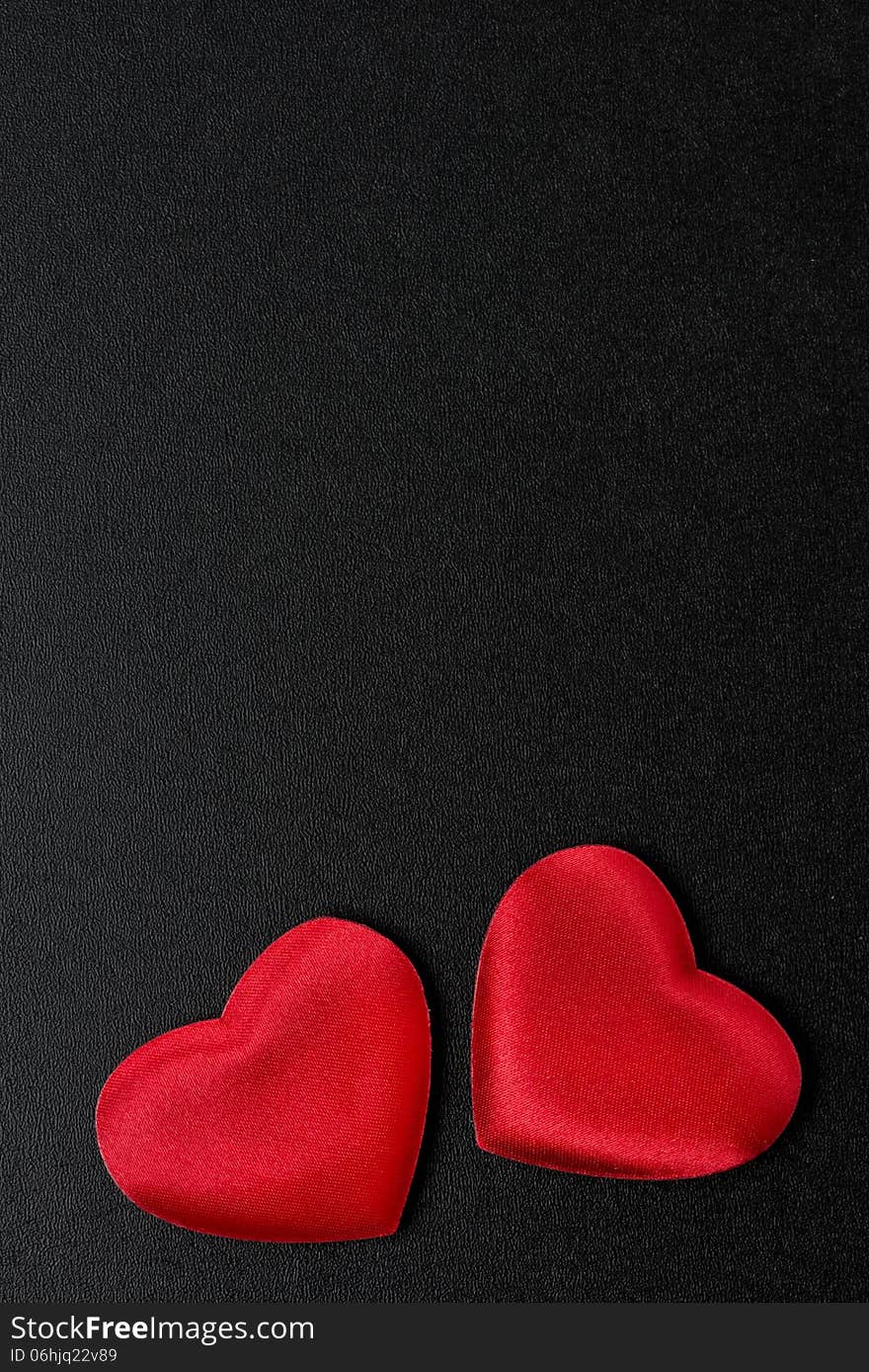 Two red hearts on a black background, top view