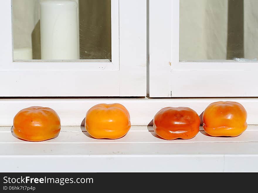 Red persimmons on white windowsill