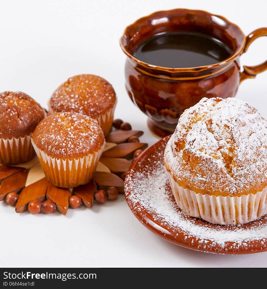 Fresh muffins with powdered sugar on a white background with a cup of coffee