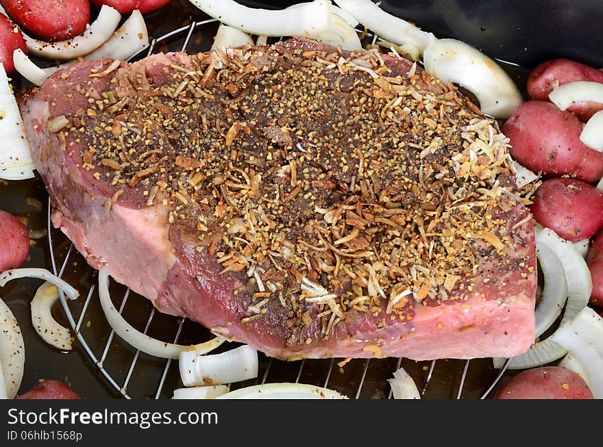 Raw meat seasoned roast with onions and potatoes