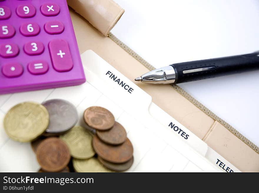 Pen point to finance page with coins and pink calculator. Pen point to finance page with coins and pink calculator