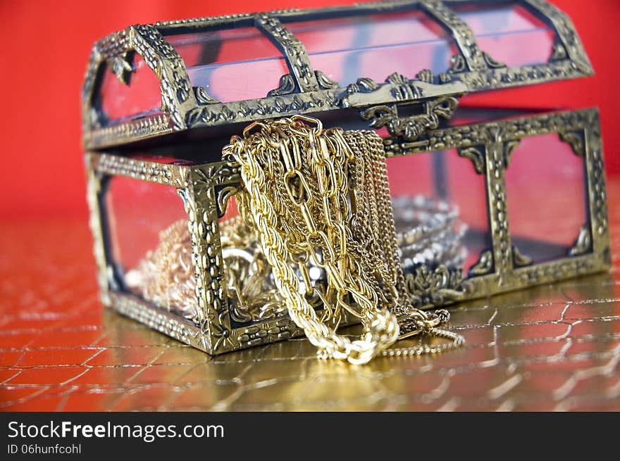 Golden jewelry in treasure chest with red background. Golden jewelry in treasure chest with red background