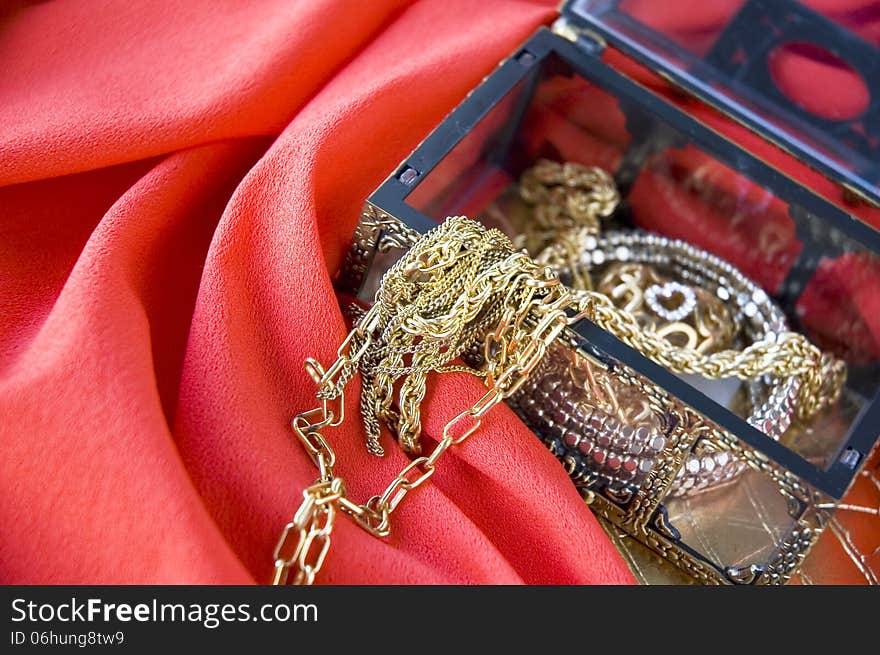 Golden jewelry in treasure chest put on red background. Golden jewelry in treasure chest put on red background