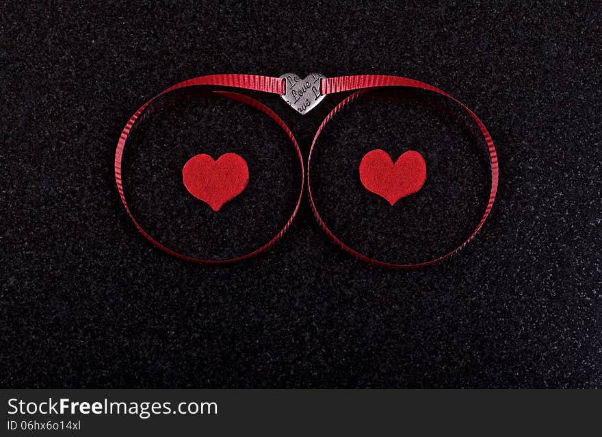 Hearts and red ribbon on black ceramic background. Hearts and red ribbon on black ceramic background