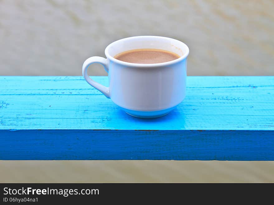 Hot coffee in white cup on wooden, During leisure time on river background