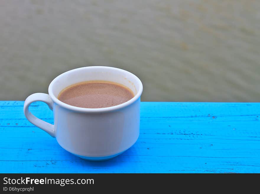 Hot coffee in white cup on wooden, During leisure time on river background