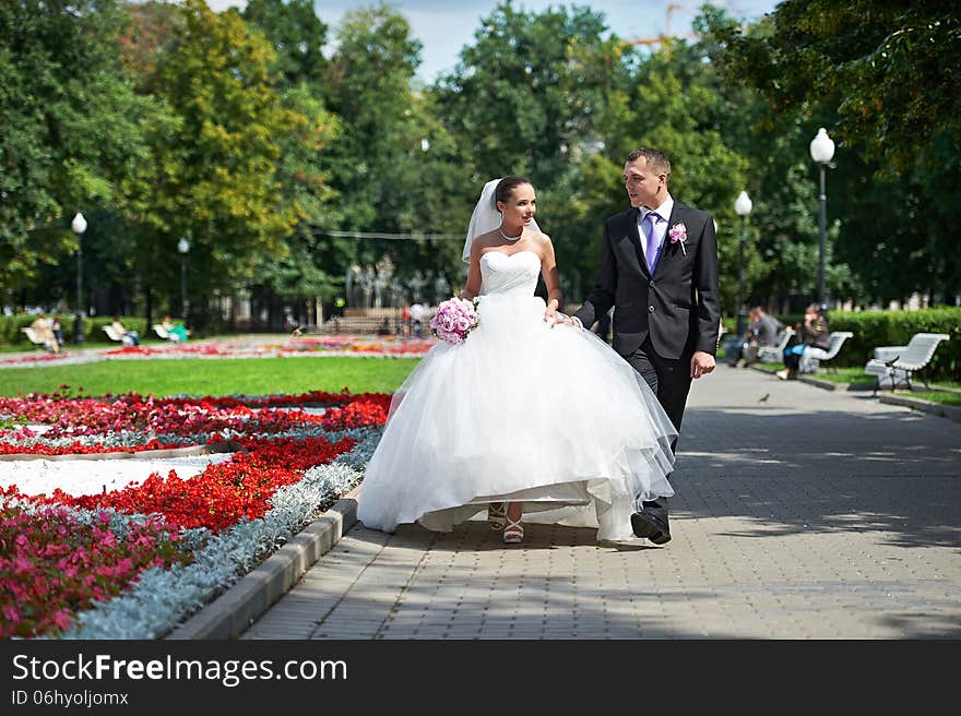 Happy groom and bride on wedding walk in park