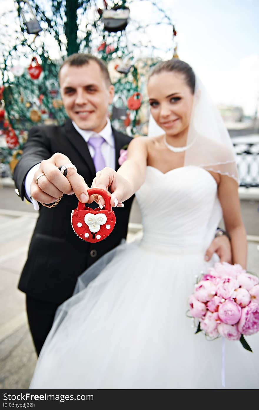 Happy bride and groom with a padlock at wedding walk