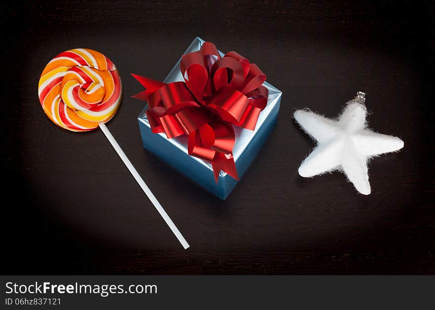 Blue gift box, candycane and white christmas star on black wooden background