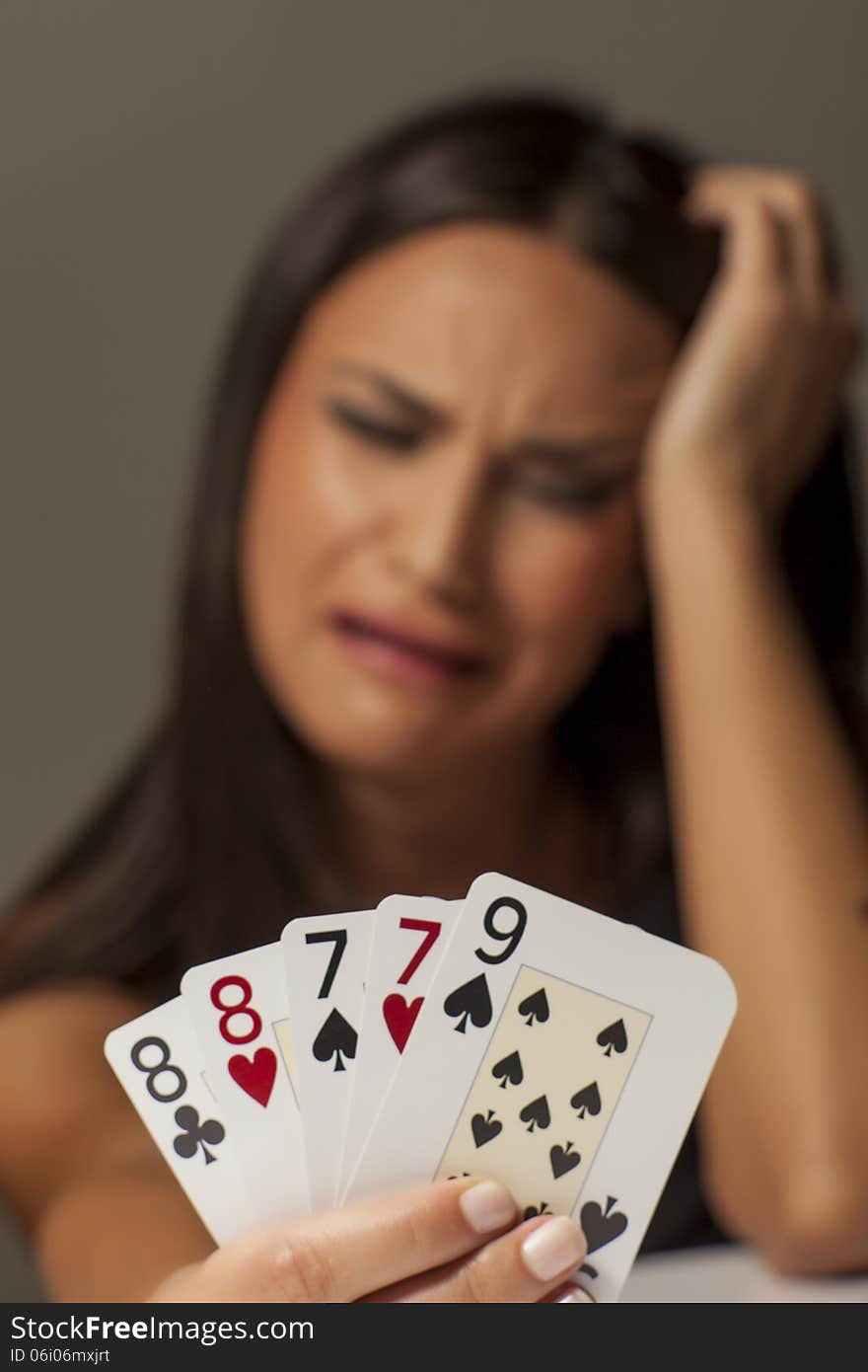 Unhappy girl holding a bad hand of playing cards