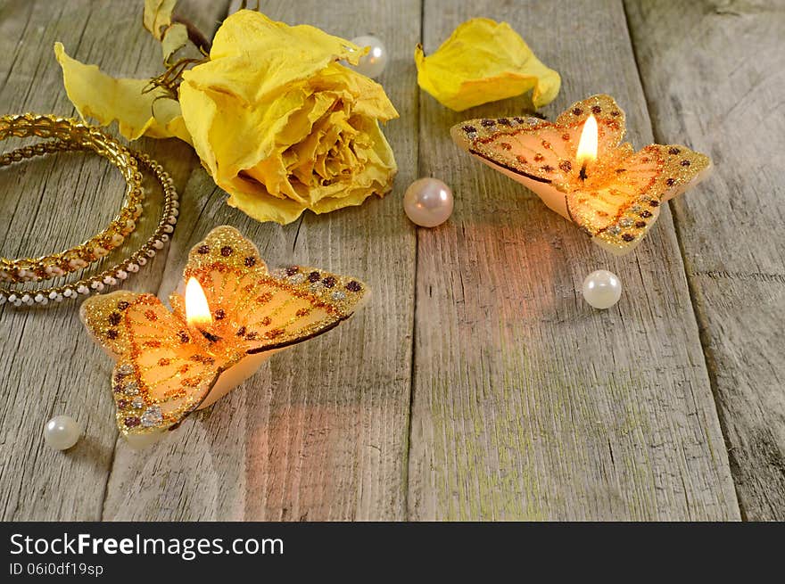 Two butterfly candles with dry rose and jewelry on wood. Two butterfly candles with dry rose and jewelry on wood