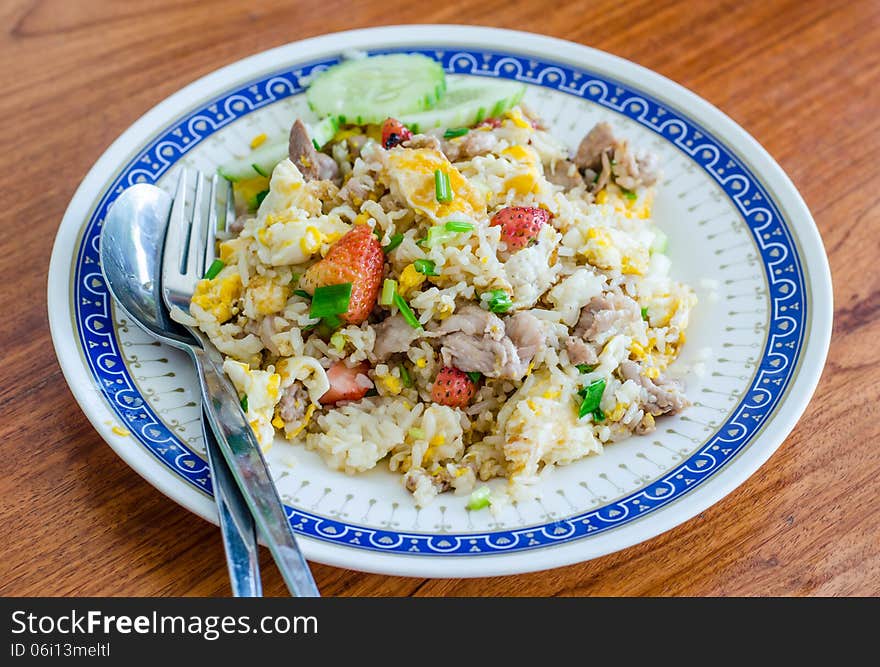 Thai style fried rice with pork ,egg and strawberry on dish for breakfast