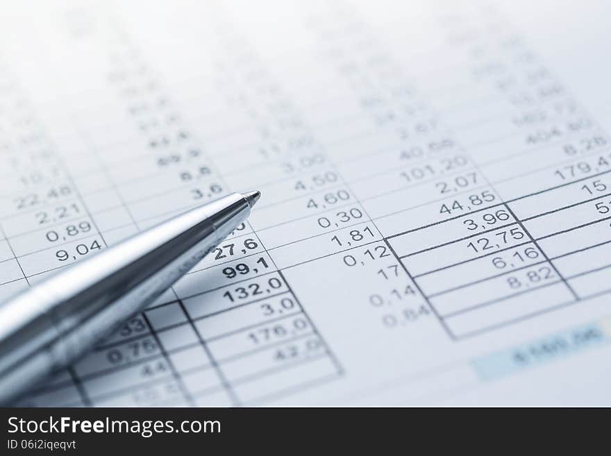 Close up of silver pen lying on the financial document with copy space. Close up of silver pen lying on the financial document with copy space