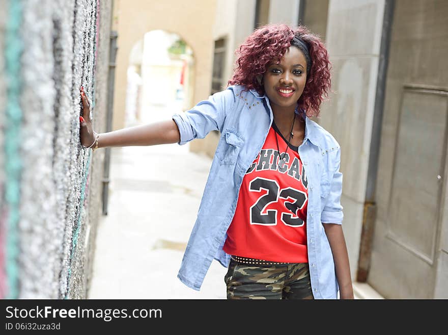 Portrait of beautiful black woman in urban background with red hair