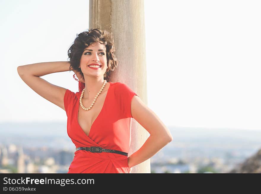 Portrait of a pretty woman, vintage style, in urban background, wearing a red dress. Portrait of a pretty woman, vintage style, in urban background, wearing a red dress