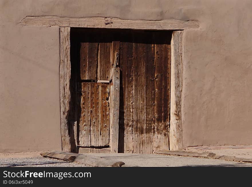 A picture of an old wooden door on an old adobe building. A picture of an old wooden door on an old adobe building.