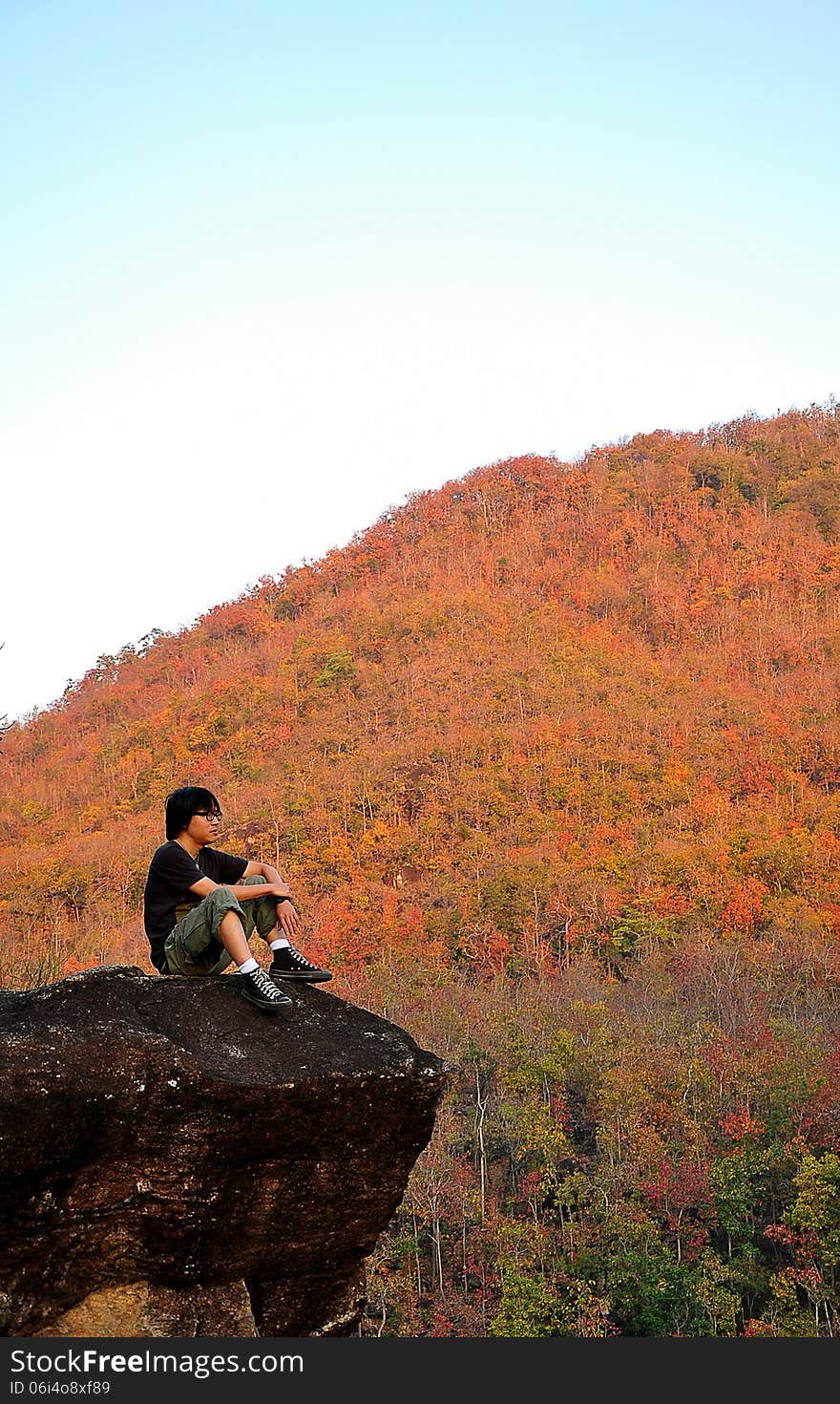 A man sitting on the cliff . A man sitting on the cliff .