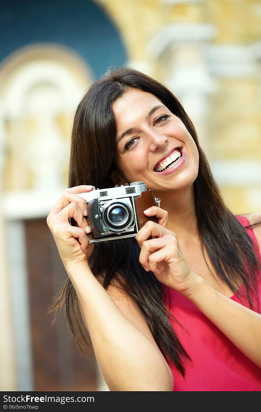 Woman on summer travel taking photo with retro film camera and smiling. Female photographer tourist on european cultural vacation. Woman on summer travel taking photo with retro film camera and smiling. Female photographer tourist on european cultural vacation.