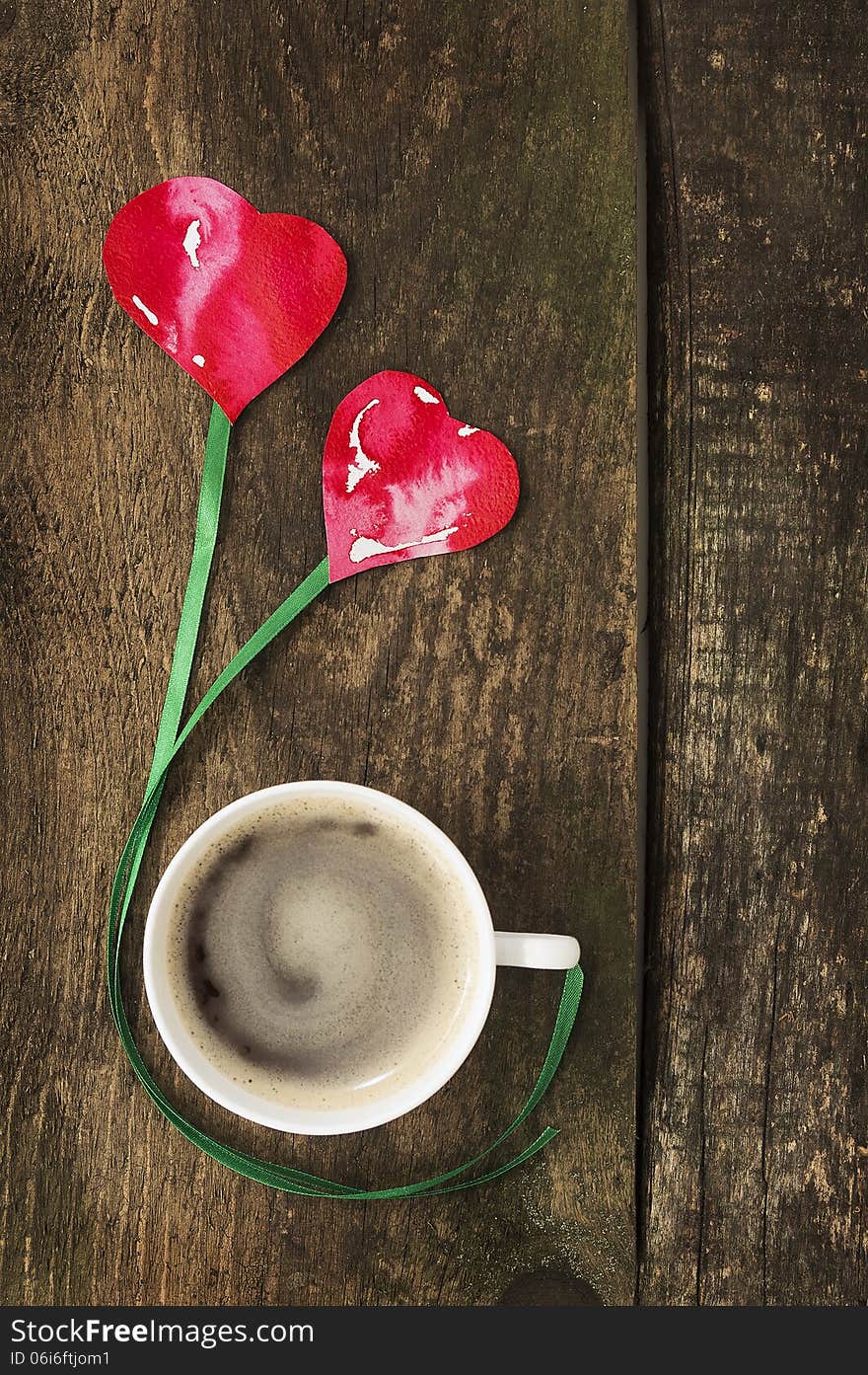 Cup of coffee with two hearts on old wooden table