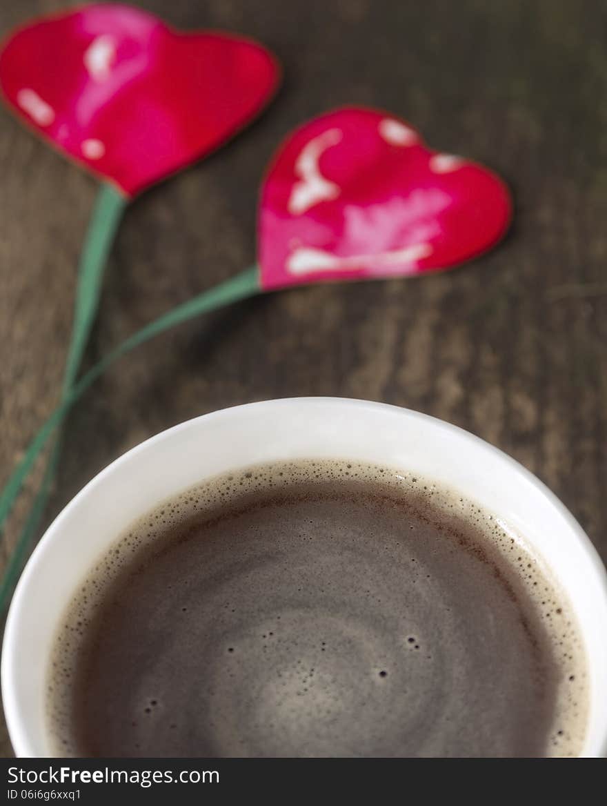 Two hearts on string, coffee cup on old wooden boards Love