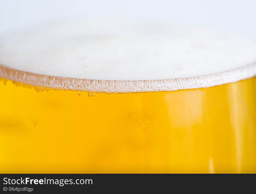 Full glass with beer and foam as background