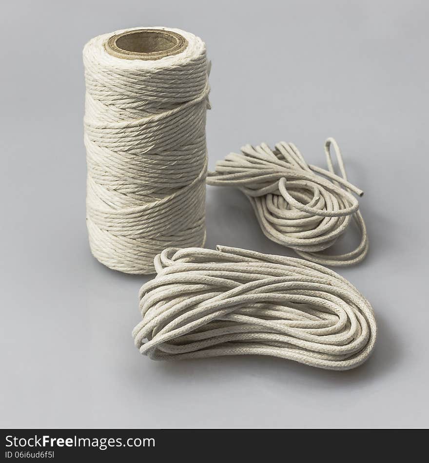 A spool with thread and strings on gray background. A spool with thread and strings on gray background.