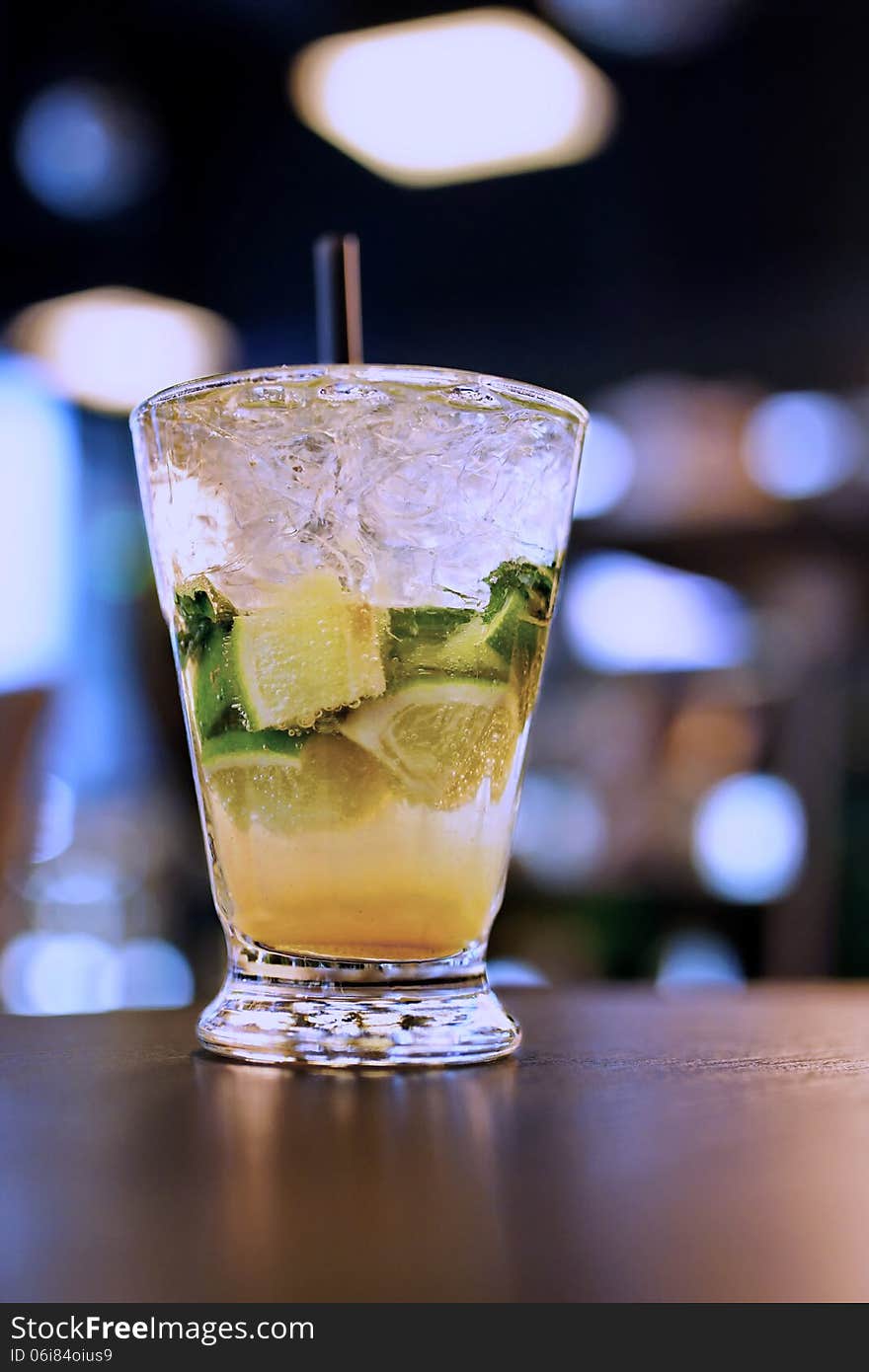 Glass with a Mojito at the table in the twilight and blurred lights in the background. Glass with a Mojito at the table in the twilight and blurred lights in the background