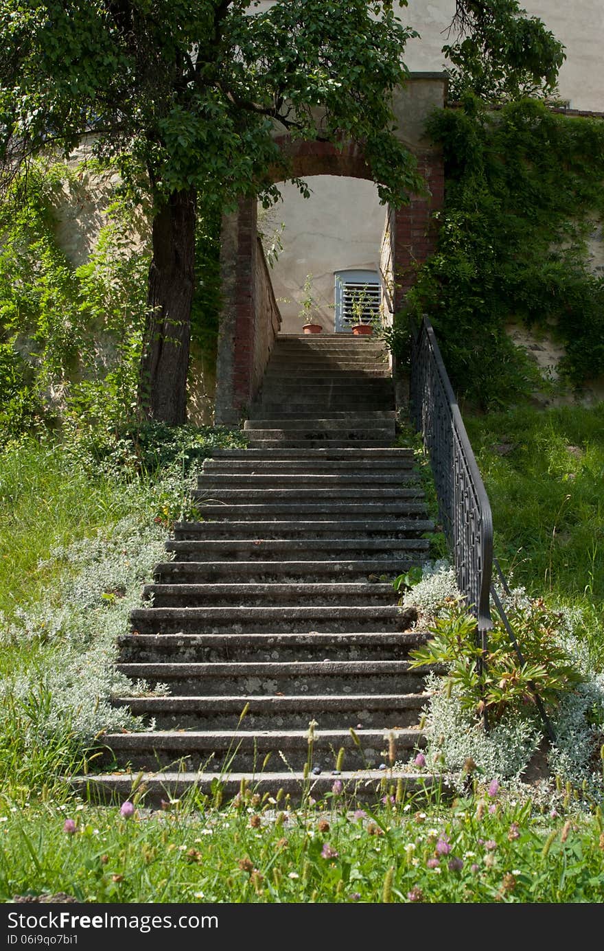 Steps with wrought iron railing, rising from grass, leading to a brick arch. Steps with wrought iron railing, rising from grass, leading to a brick arch