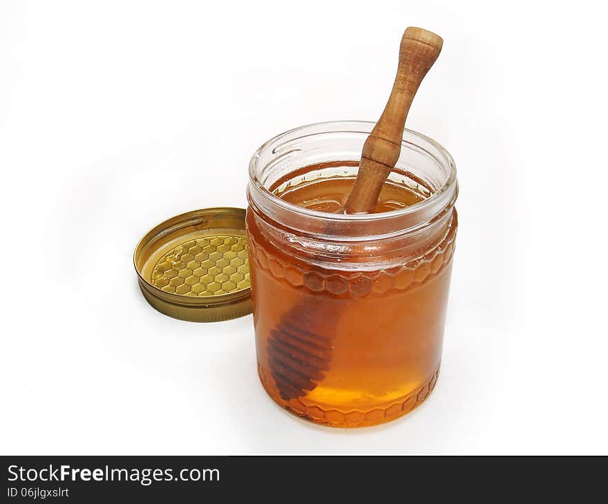 Honey glass jar with lid and wooden drizzler isolated on white background. Honey glass jar with lid and wooden drizzler isolated on white background