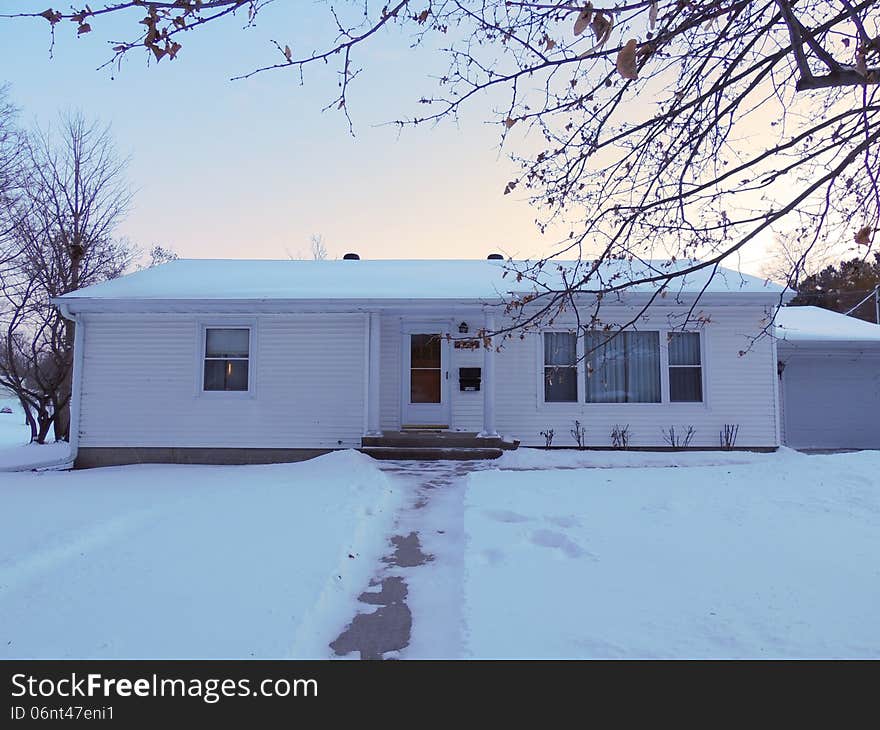 A generic type white ranch home in the winter. For use for exterior maintenance and cleaning service or snow removal and lawn care. Home is attractive, but in need of a pressure wash to look its best. This could also serve for real estate or insurance advertising. Picture was taken at sunset in soft light. A generic type white ranch home in the winter. For use for exterior maintenance and cleaning service or snow removal and lawn care. Home is attractive, but in need of a pressure wash to look its best. This could also serve for real estate or insurance advertising. Picture was taken at sunset in soft light.