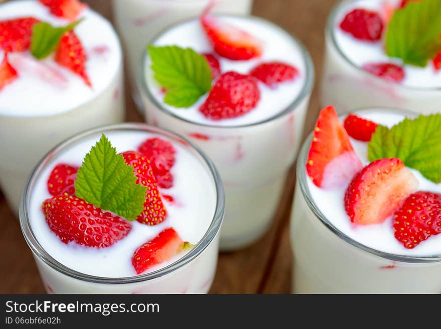 Glasses of strawberry yogurt with strawberry pieces on top.