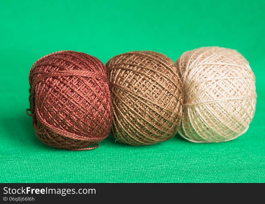 Some balls of a multi-colored yarn on a green background close up