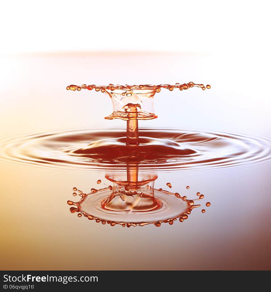 Splashing water drops on color background.Color waterdrops collide each other.A small water drop fall on water surface and jump back before the second one to collide with it.