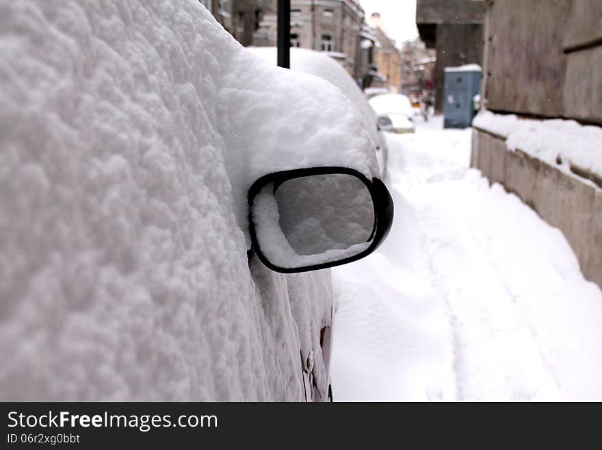 Car covered in snow and the only part visible of the car is the mirror. Car covered in snow and the only part visible of the car is the mirror