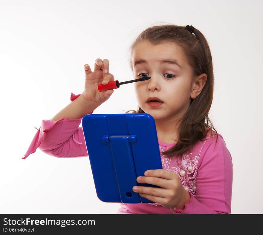 Cheerful girl colors eye makeup in the mirror