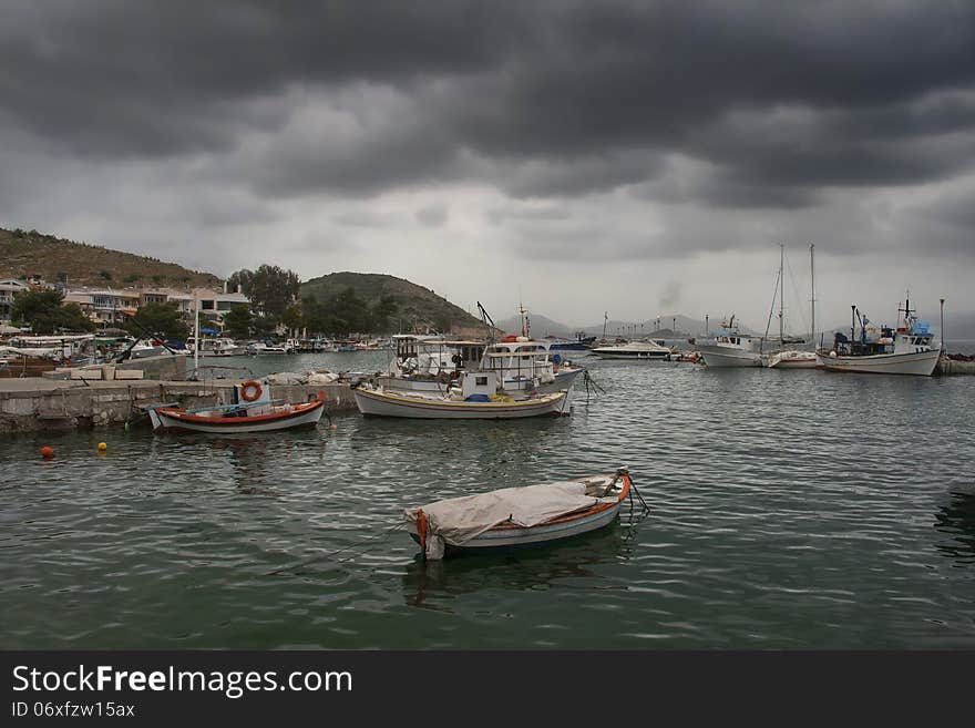 A view of a quiet fishing harbor in foggy morning with the seagulls above.Pachi village 45 km from Athens,Greece. A view of a quiet fishing harbor in foggy morning with the seagulls above.Pachi village 45 km from Athens,Greece