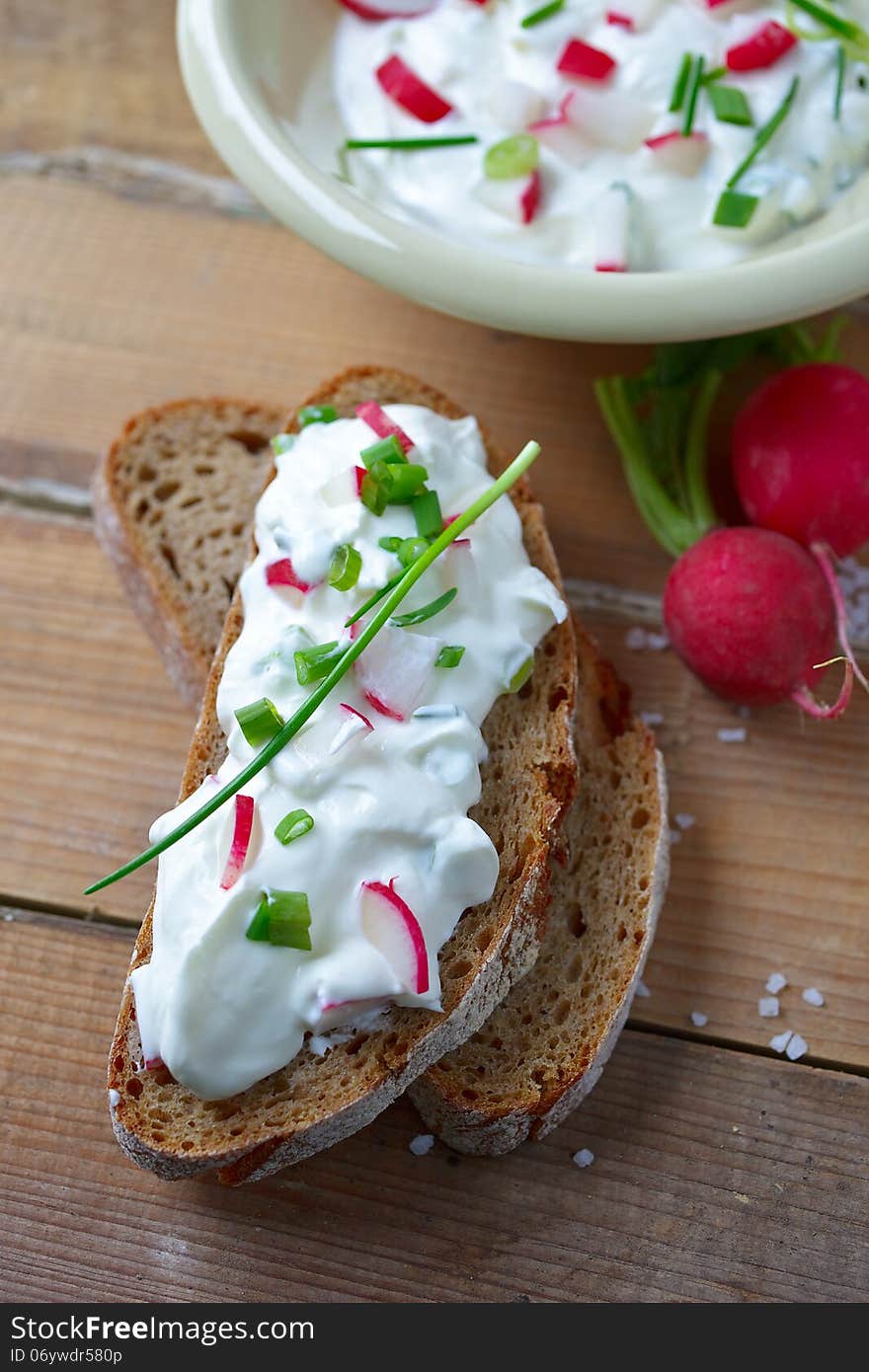 Delicious bread with soft cheese, radish and greens on wooden board. Delicious bread with soft cheese, radish and greens on wooden board