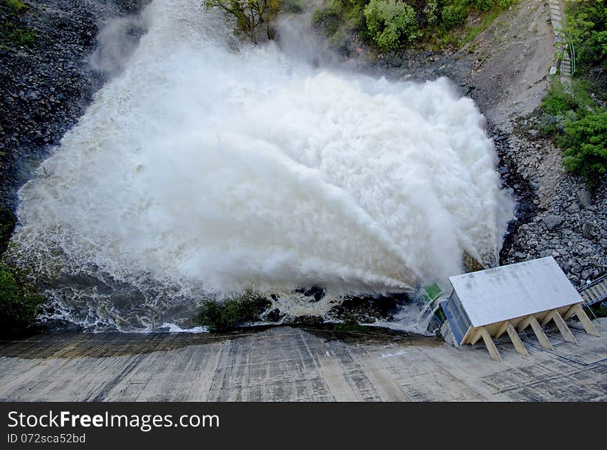 An impressive view of a dam releasing a massive surge of water through its spillway, creating a dramatic cascade. Surrounded by greenery and rugged terrain, this scene showcases the raw power of controlled water discharge, essential for flood management and energy generation. A striking display of nature and engineering in harmony. An impressive view of a dam releasing a massive surge of water through its spillway, creating a dramatic cascade. Surrounded by greenery and rugged terrain, this scene showcases the raw power of controlled water discharge, essential for flood management and energy generation. A striking display of nature and engineering in harmony.