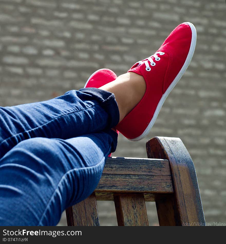 Red shoes and blue denim in park bench