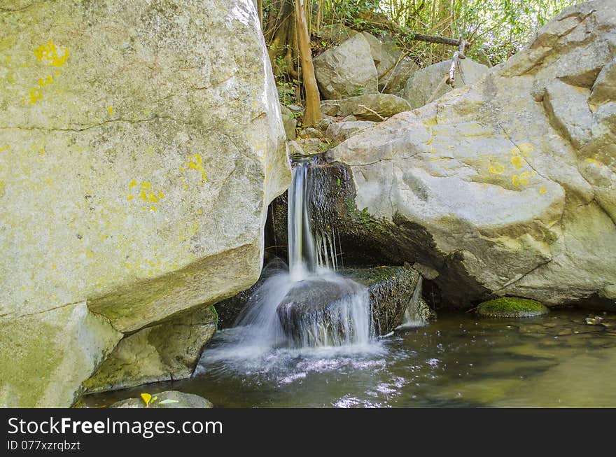 Small Waterfall Flowing Between Large Rocks in a Forest