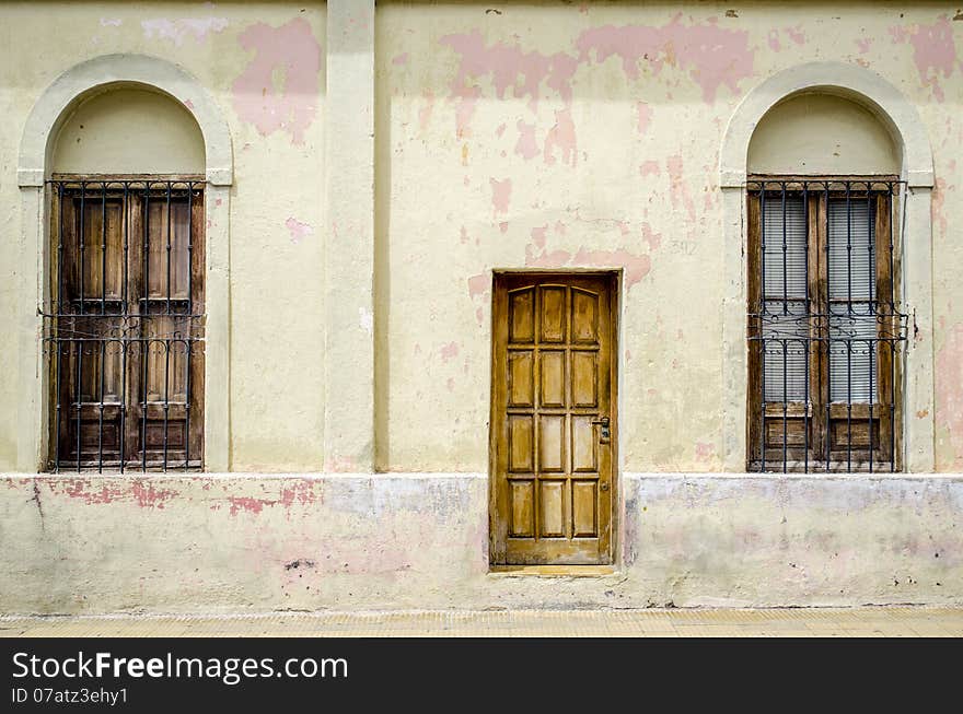 Aged Colonial Facade with Wooden Door and Arched Windows