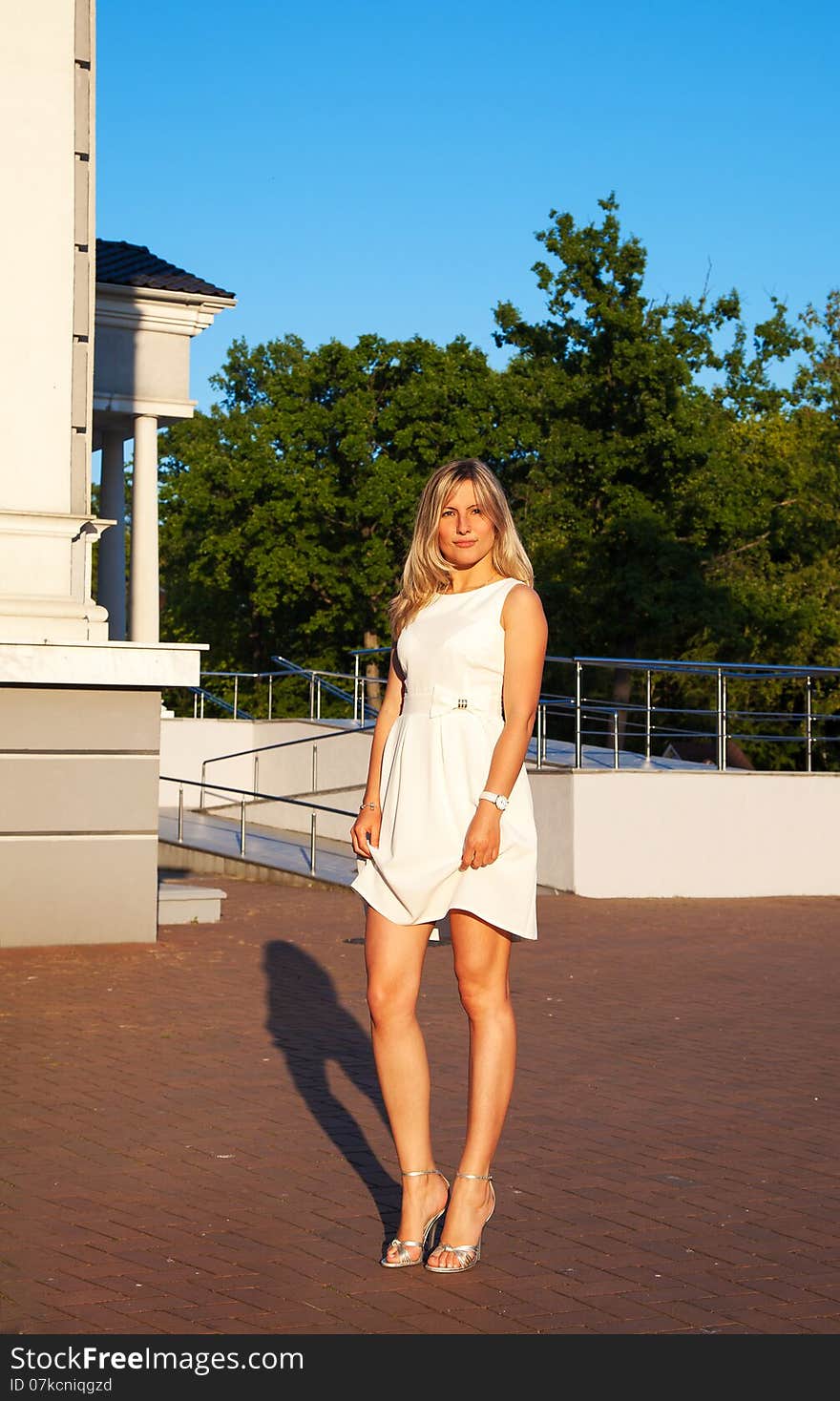 young woman in white dress posing standing in a park