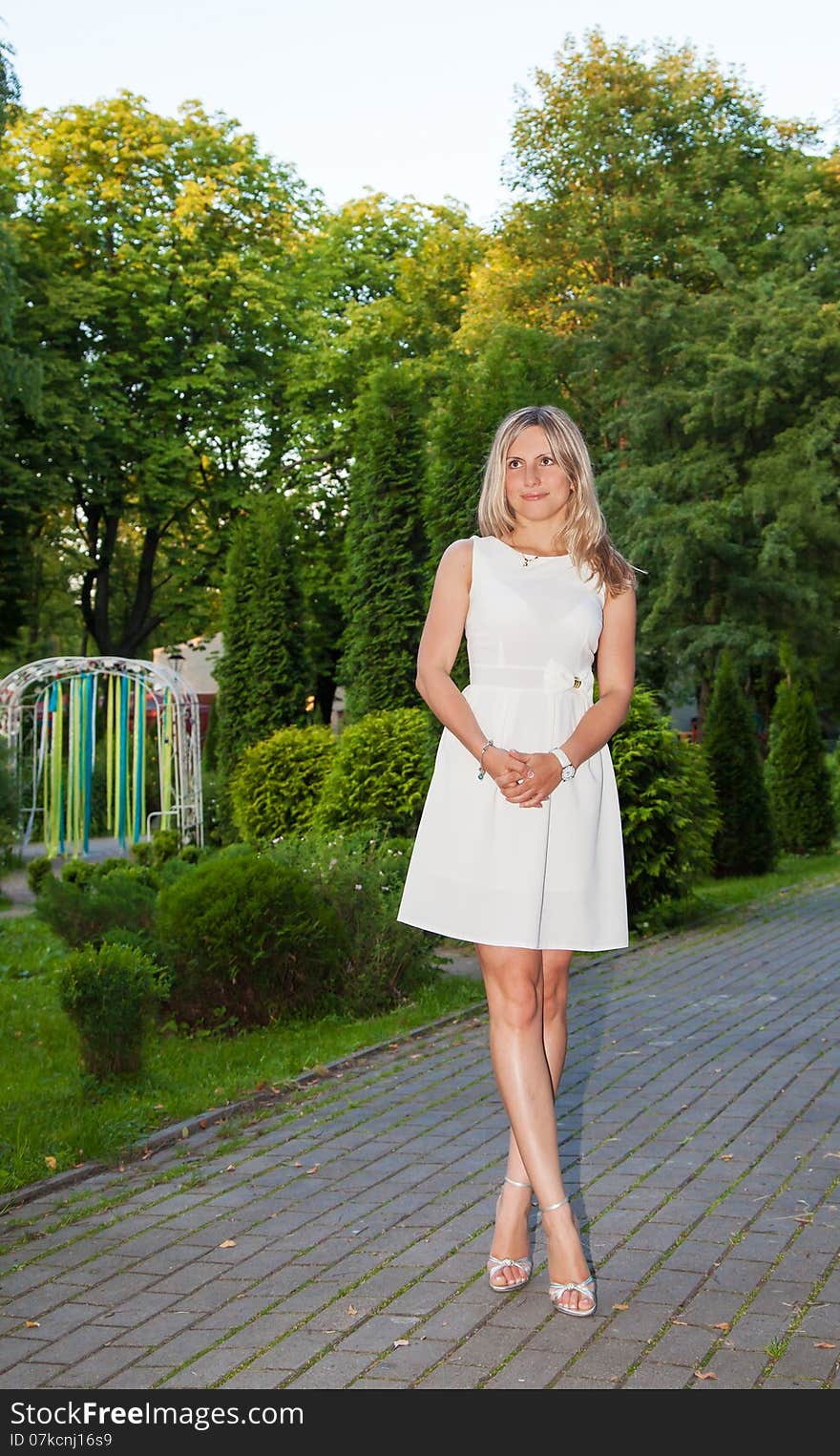 Young woman in white dress posing standing in a park