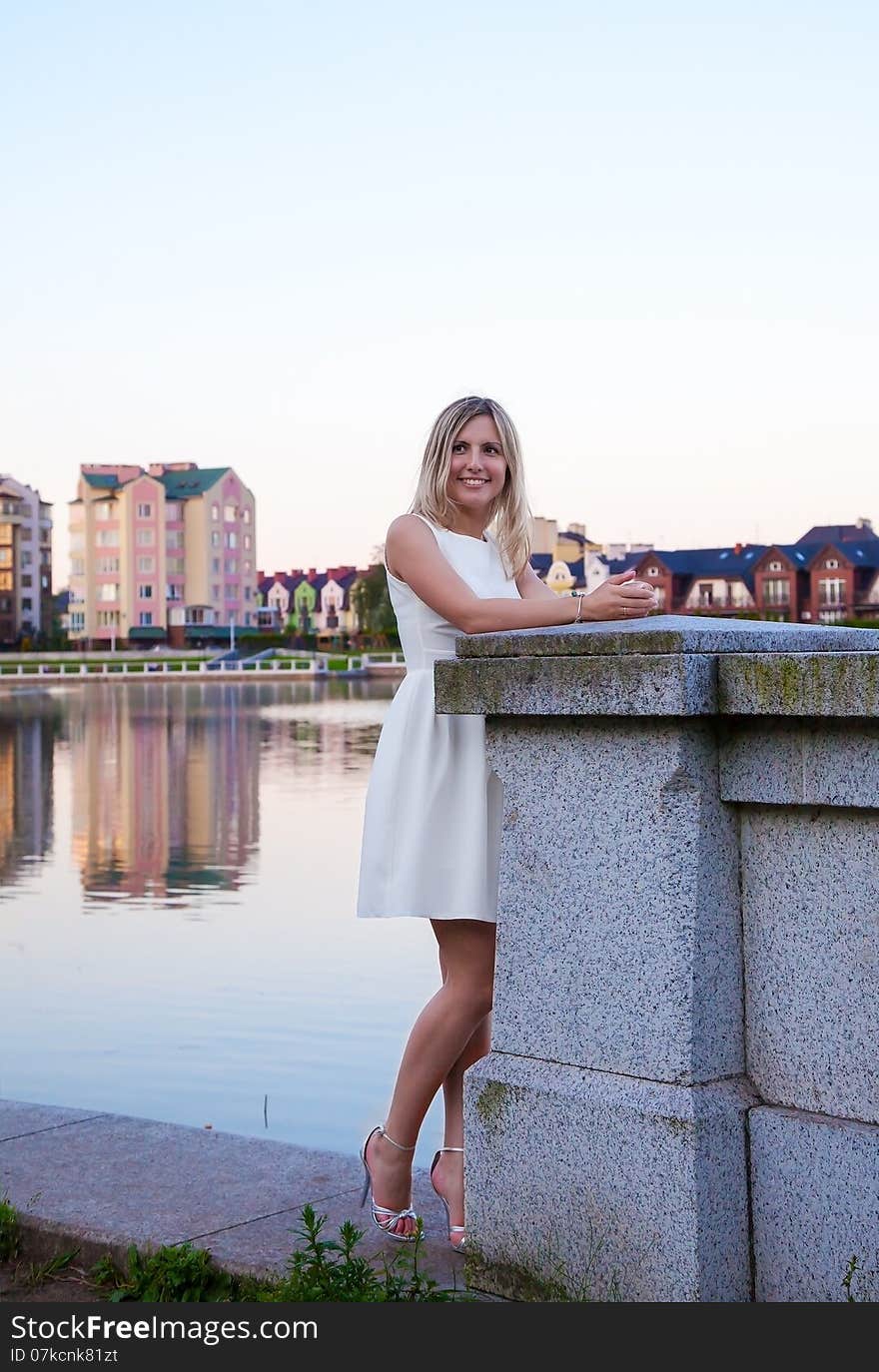 Beautiful woman in a white dress standing on the waterfront