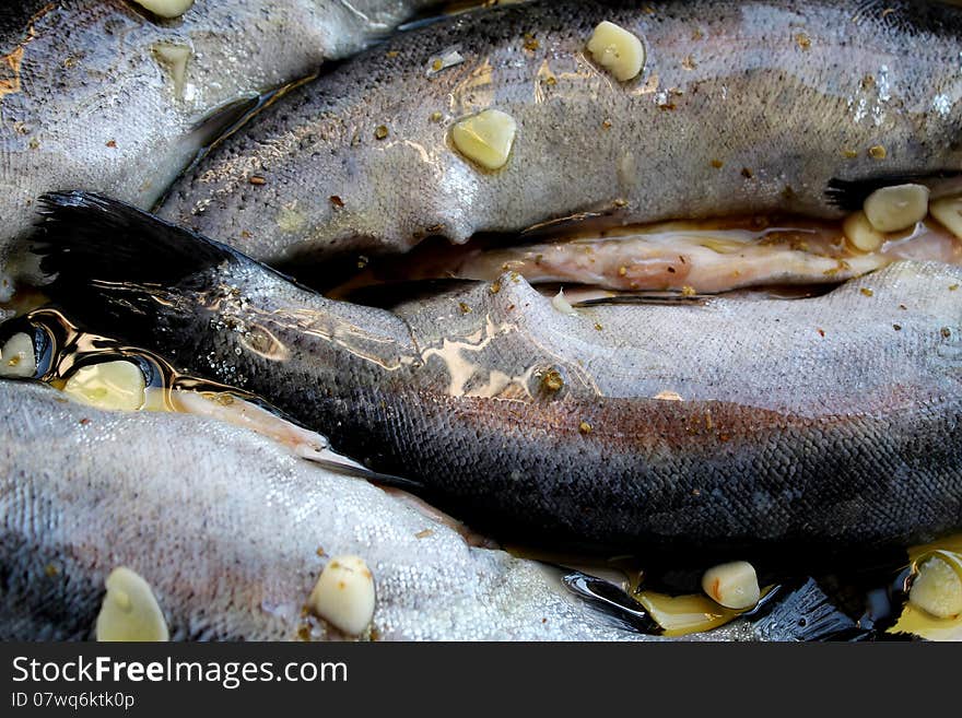 Trout with garlic and olive oil in ceramic bowl ready to be placed in the oven