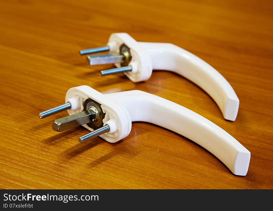 Two white handles for plastic windows on the table closeup