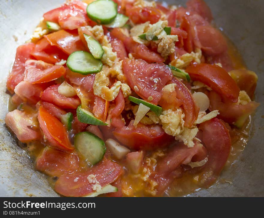 Close-up of home cooking of tomato cucumber and eggs cooking together in the wok. Close-up of home cooking of tomato cucumber and eggs cooking together in the wok