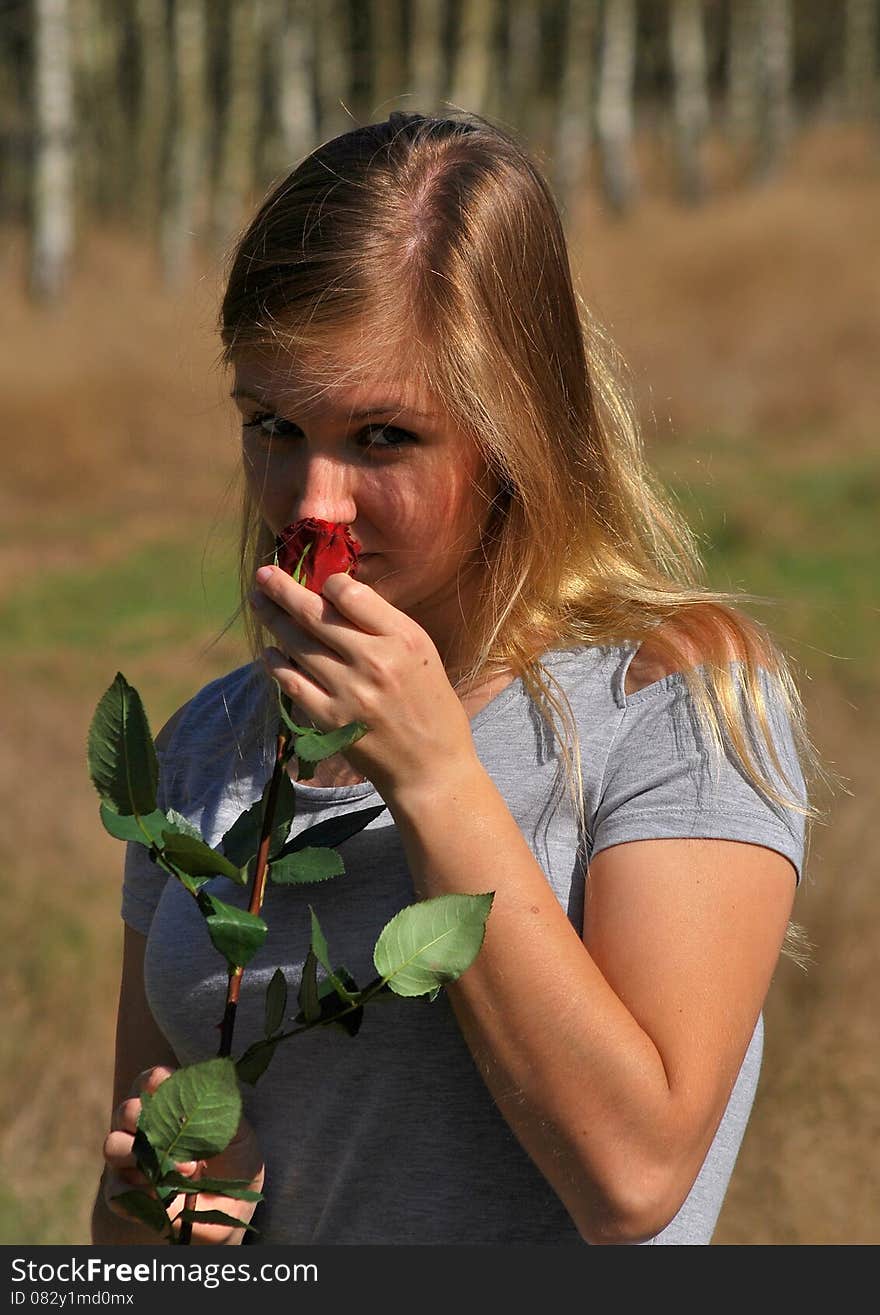 Beautiful young woman holding in hand a red rose